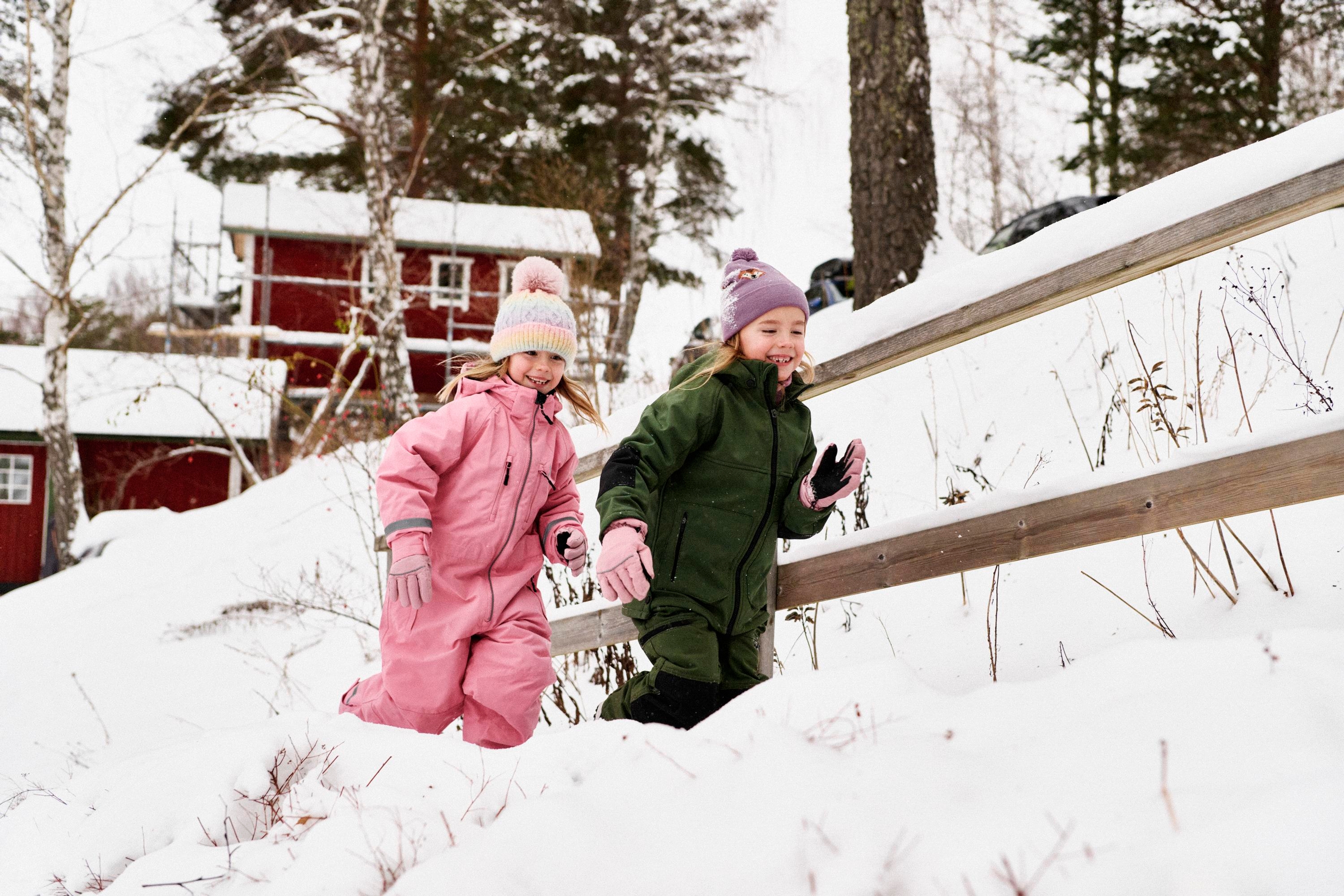 Två barn springer i snön